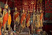 Wat Xieng Thong temple in Luang Prabang, Laos. standing Buddha statues in the  calling for rain  mudra with both arms down at sides and palms against thighs. Royal Funerary carriage hall. 